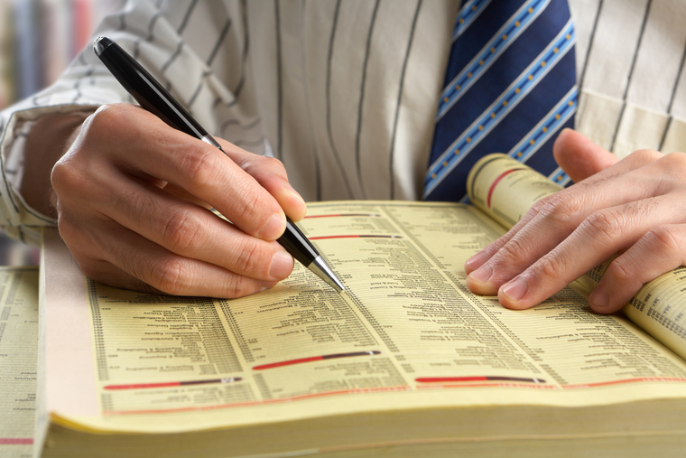 Businessman searching something in yellow pages by index